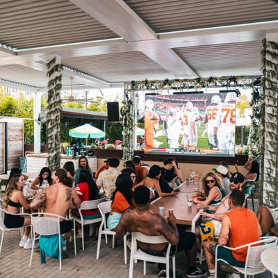 Group of people enjoying a football game day event at an outdoor patio.