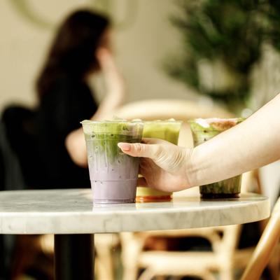 A server places layered iced drinks on a marble table.