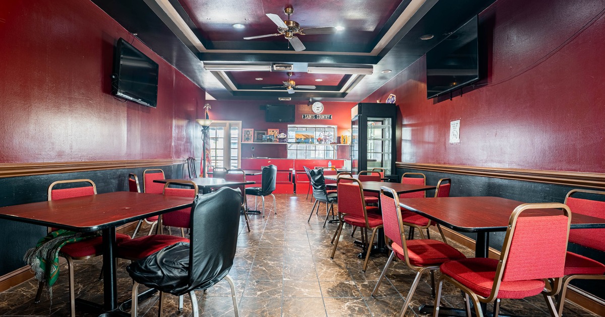 Interior of a small restaurant featuring red walls, several tables with red and black chairs