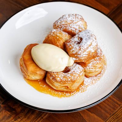Plate of beignets with cream and powdered sugar.