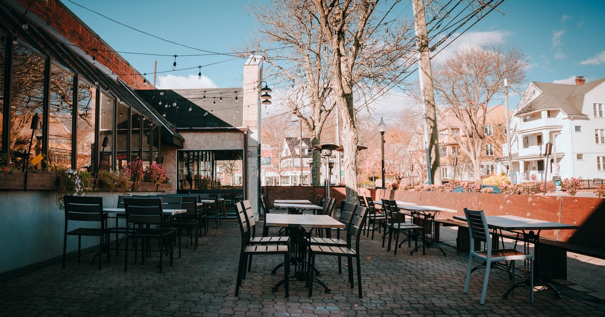 Exterior, patio, cobblestone flooring, tables and chairs, wooden banquette bench