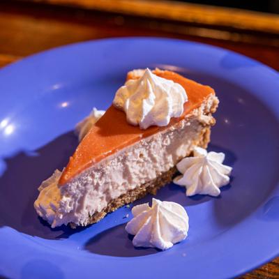 Guava Cheesecake served on a blue plate with whipped cream.