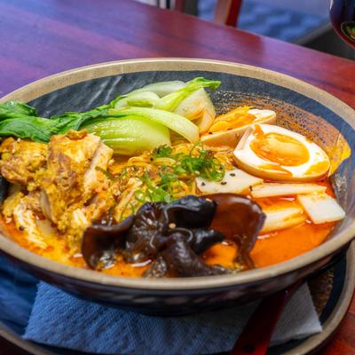 Thai ramen with chicken, mushrooms, bok choy, and a soft-boiled egg.