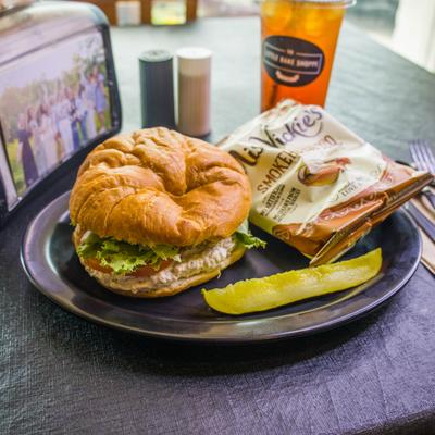 Chicken Salad and Cheese bagel served with a bag of chips and a pickle spear.