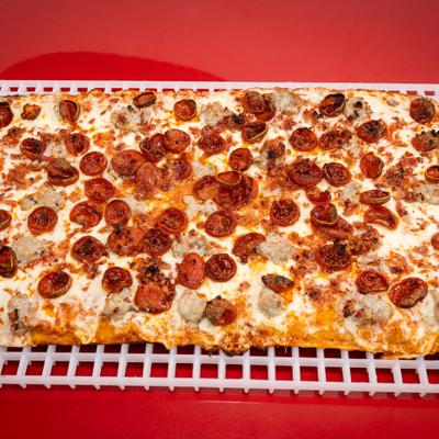 Meat lover rectangular pizza served on plastic baking screens.