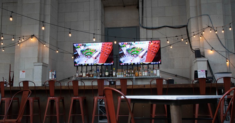 Exterior, outdoor bar, wooden counter top, bar stools, large concrete block wall in the back