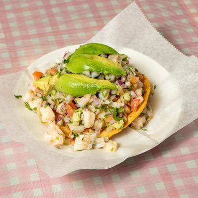 Ceviche tostada topped with avocado slices.