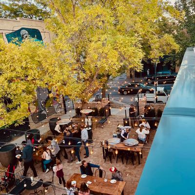 Outdoor courtyard dining with string lights, trees, and people seated.
