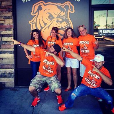 Fans in orange jerseys pointing upwards posing for a photo