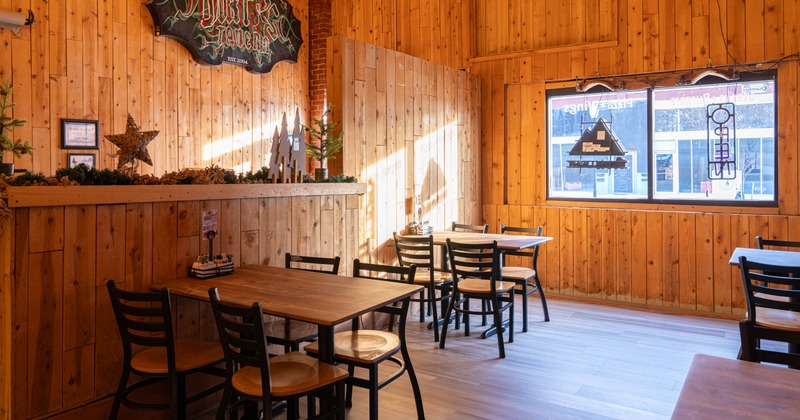Interior, dining area, wooden top tables for four, wood coated walls, small window