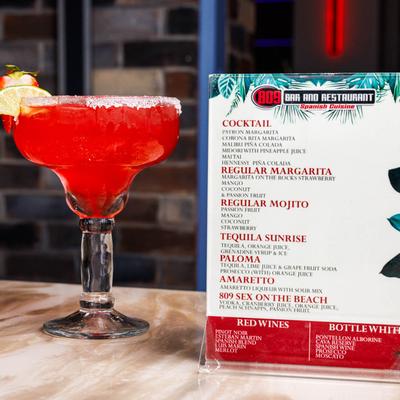 Strawberry margarita next to 809 Bar and Restaurant cocktail menu.