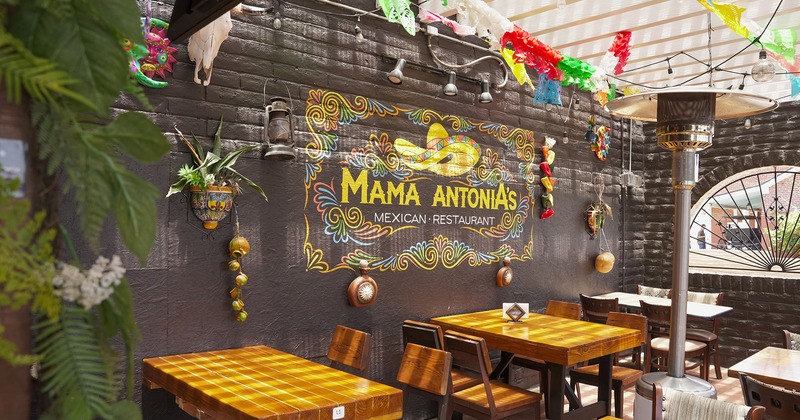 Covered patio, dining tables lined up, restaurant's logo on the wall