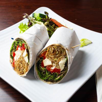 Vegetable wrap sliced in half and served with a salad on the side.