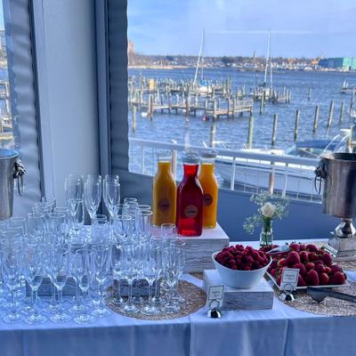 Event setup featuring a beverage and fruit display overlooking a marina.