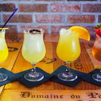 Tropical cocktails with citrus and strawberry garnishes on a wooden table.