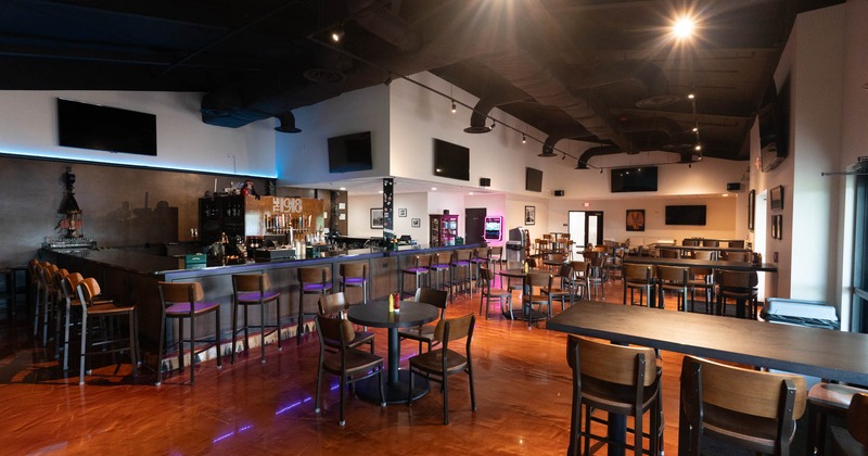 Interior, seating area, multiple TVs hanged on the wall, bar with bar stools