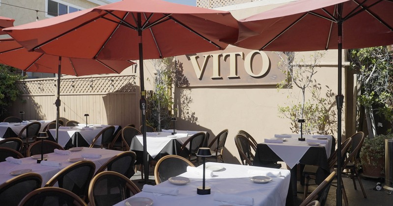 Exterior, patio dining area, white cloth tables for four and six, broad red parasols