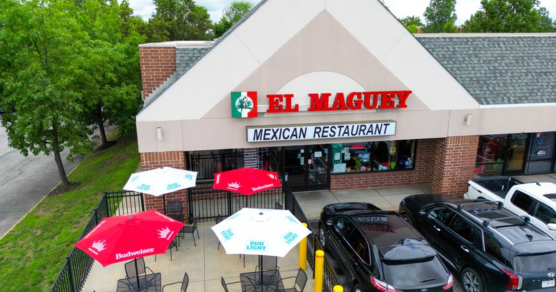 Aerial point of view. restaurant, entrance, part of parking lot with cars, patio, parasols