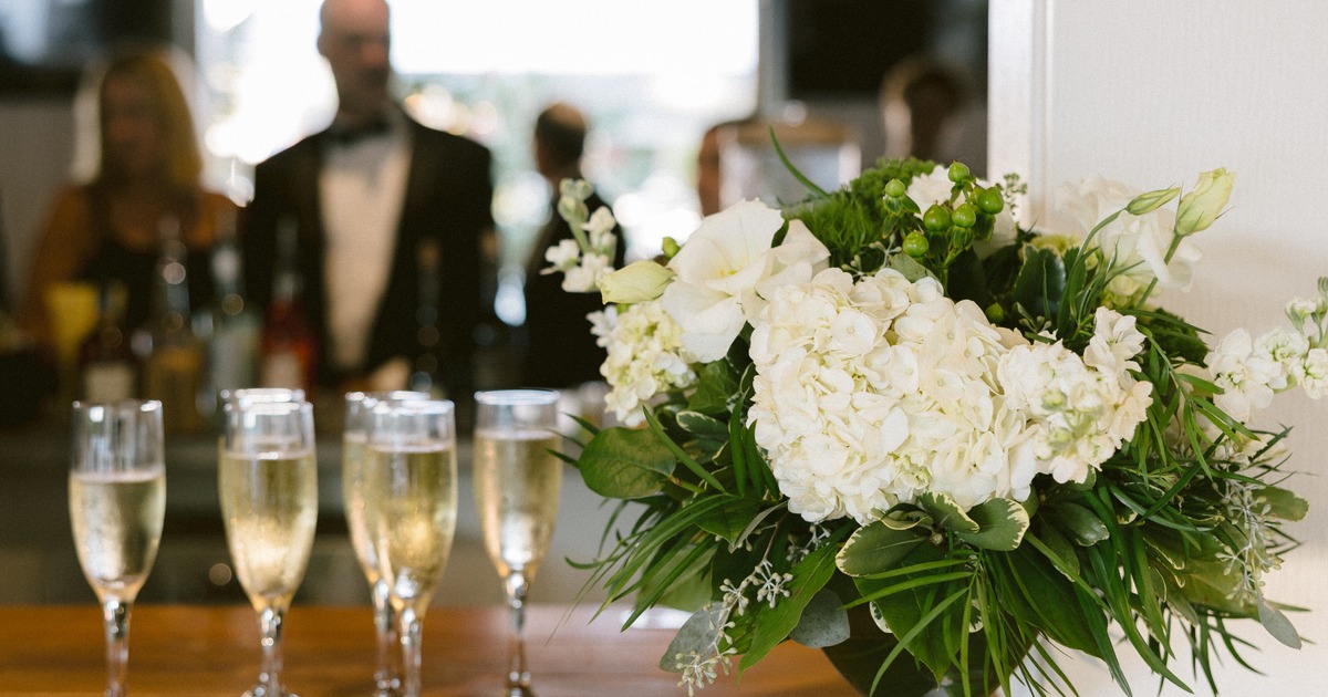 Filled champagne glasses beside a white floral arrangement