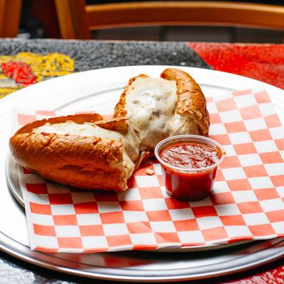 Meatball sub sandwich and marinara sauce on a plate with checkered paper.