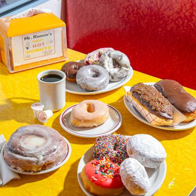 Assortment of donuts and coffee on a yellow diner table with a red seating background.