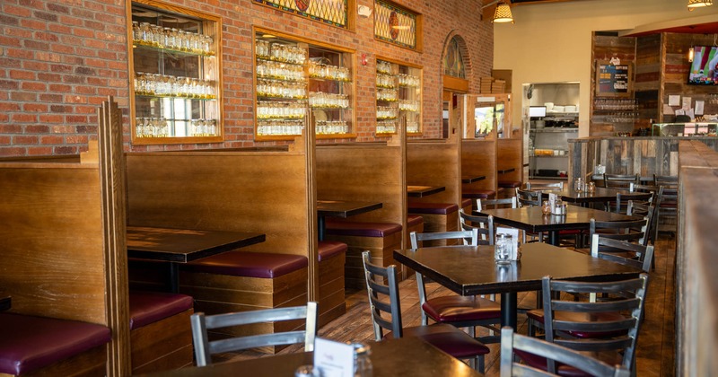 Interior of a restaurant with wooden booths and tables and stained glass decor
