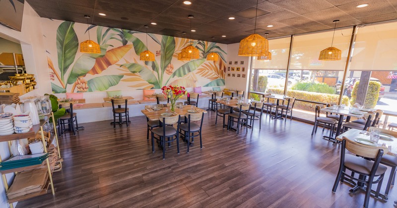 Cozy restaurant interior with wooden tables and large windows.