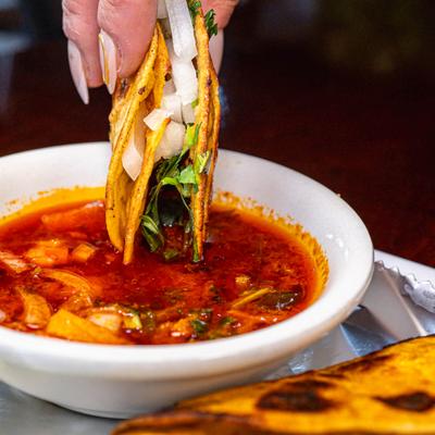 Crispy quesabirria taco dipped into consommé broth.