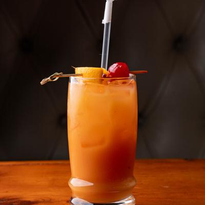 Tequila Sunrise garnished with orange and a cherry.
