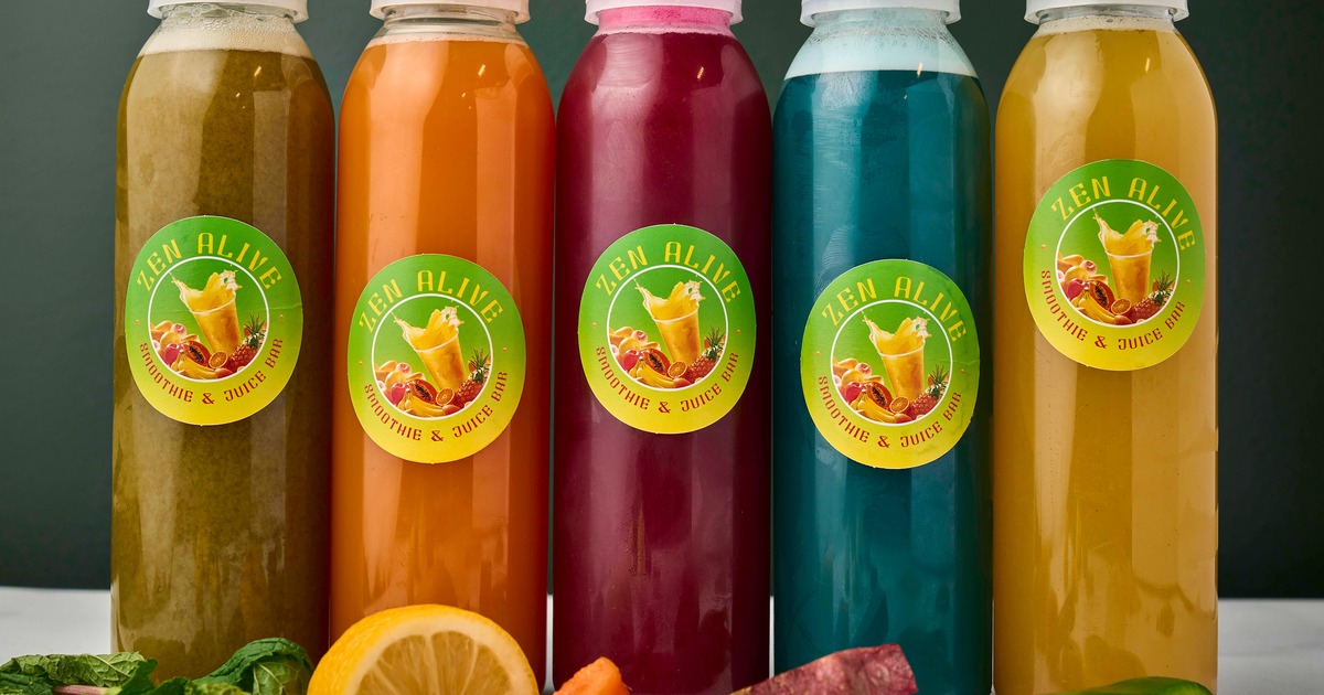 Various bottles of cold-pressed juices alongside fresh fruits and vegetables