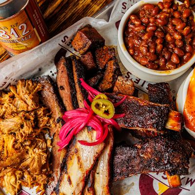 Barbecue platter served with baked beans and a can of house-brewed beer.