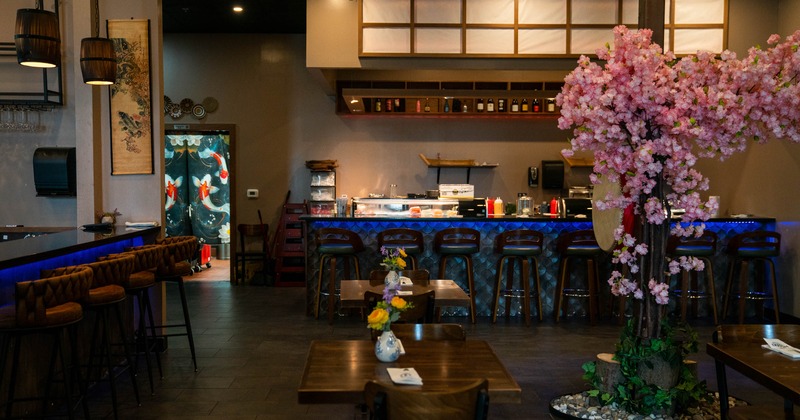 Interior - a sushi bar, wooden tables, koi artwork, a large pink cherry blossom arrangement
