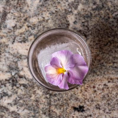 Japanese Botanical Garden cocktail, garnished with a lavender and white pansy flower.