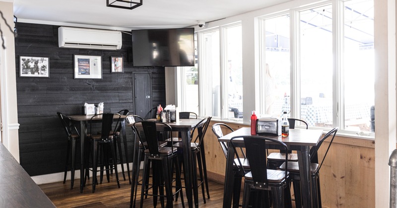 Interior, tall tables and bar chairs by a window, TV