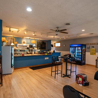 Inside the cafe with blue walls, light hardwood floors, and tables and chairs for diners.