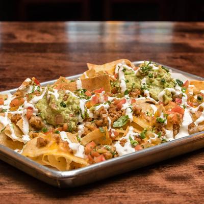Nachos, with melted cheese, pico de gallo, sour cream, and guacamole.