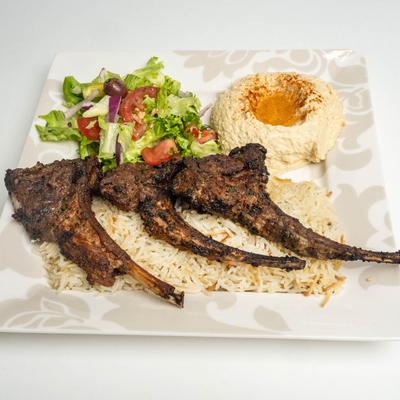 Lamb chops, rice, hummus, and salad.