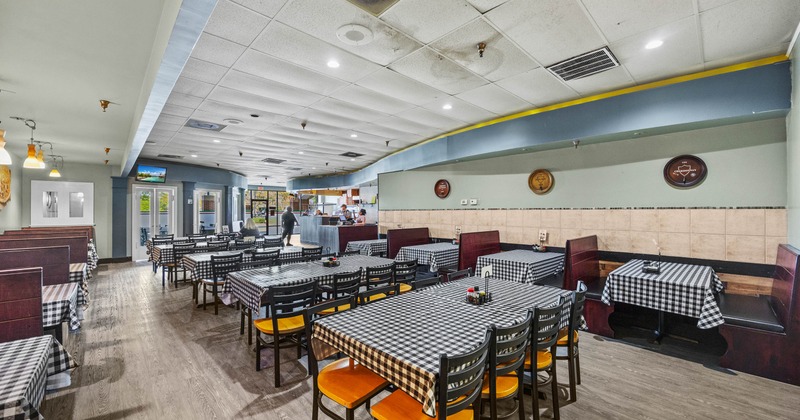 Inside,  tables with checkered tablecloths, wooden booths, and a counter area in the background
