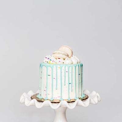 Funfetti vanilla cake with blue chocolate drip and vanilla macaron on top.