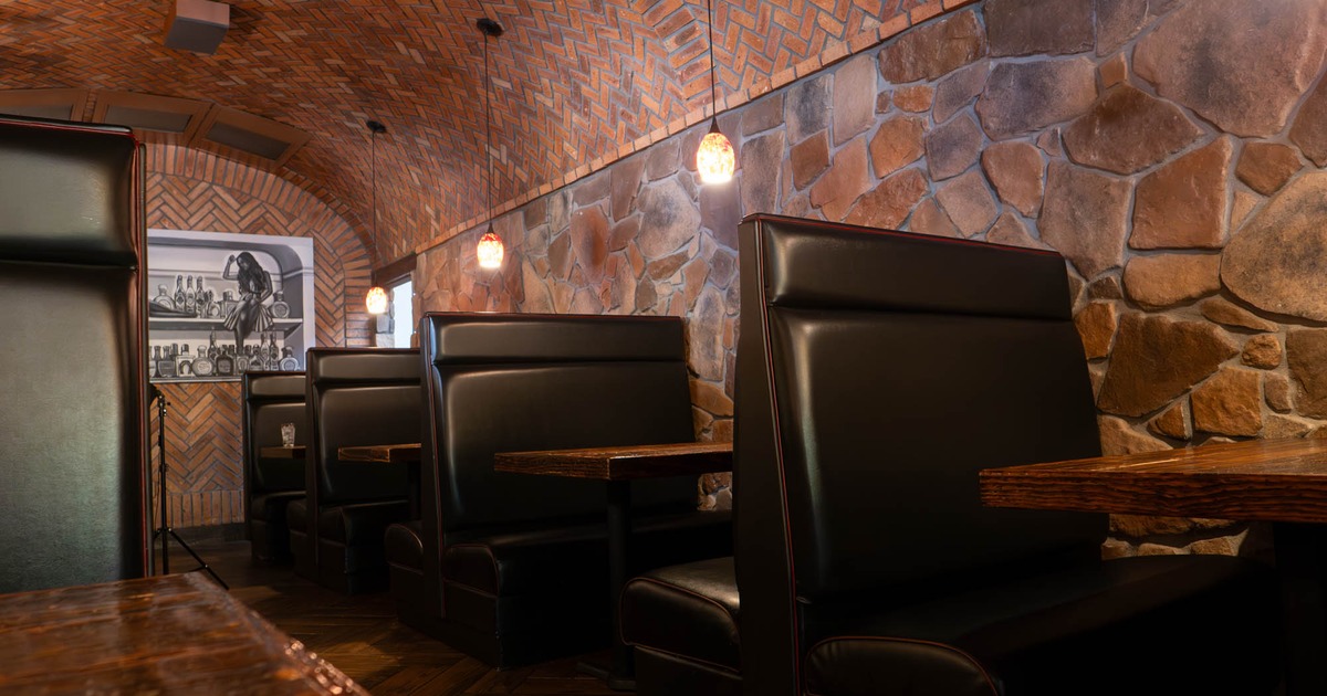 Interior, dining area, padded seating booths with wooden top tables, stone walls