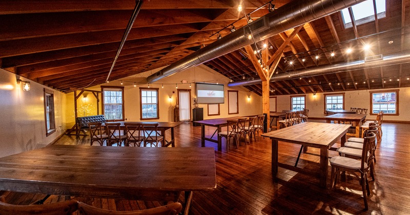 Interior with wooden tables and chairs; wooden beam roof with hanging lighting.