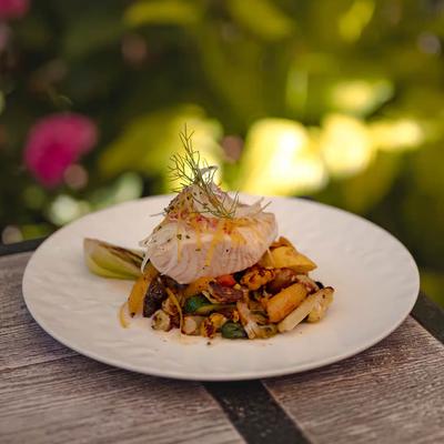 White fish fillet resting on a bed of roasted vegetables.