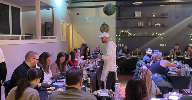 People sitting at tables learning how to prepare food