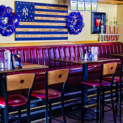 Dining tables and seating by a wall decorated with wreaths and a  NY Yankees wooden flag.