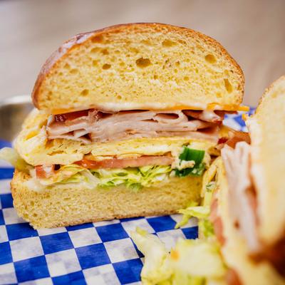 A close-up of a breakfast sandwich layered with turkey, lettuce, tomato, and egg.