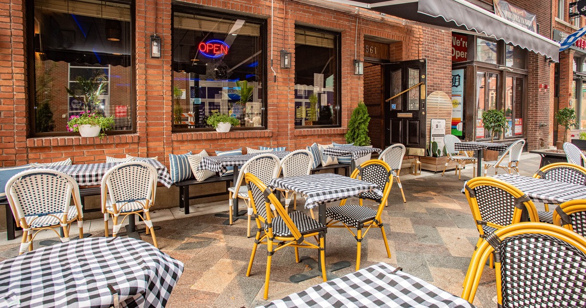 Outdoor restaurant dining area with checkered tables, brick walls