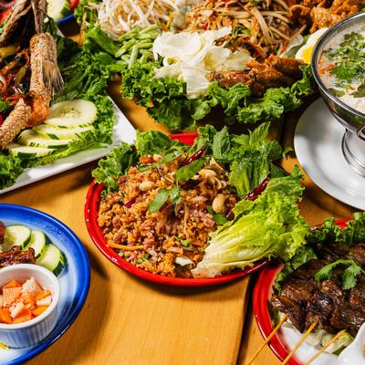 Assorted Thai dishes served on colorful plates with fresh herbs and vegetables.