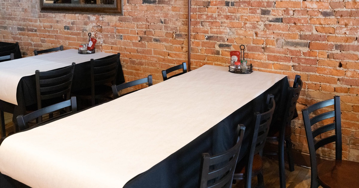 Dining area with a long table, brick walls, and wooden chairs