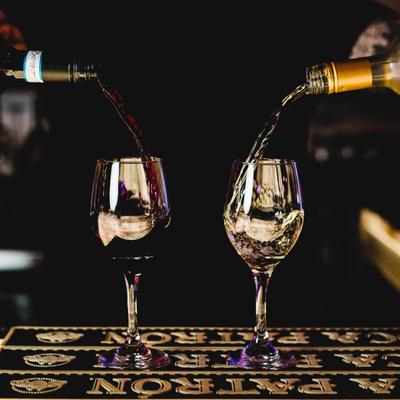 Two wine glasses being filled with red and white wine.