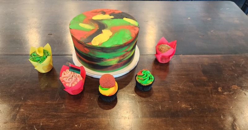A colorful cake surrounded by cupcakes